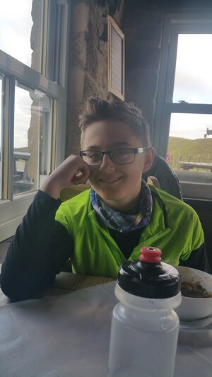 Boy sitting in a café elbow on table and smiling.